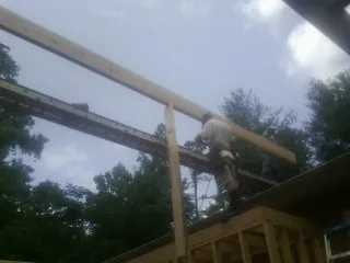 Carpenter setting a ridge beam over a new addition frame — Ice Dam Removal by Roofing Brothers in Hope